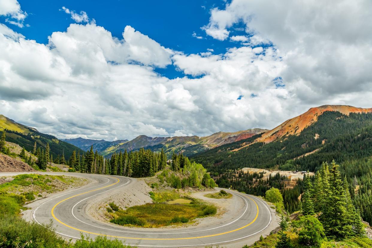 San Juan Mountain Skyway, Colorado, curving through the mountains with the blue sky and clouds in the background