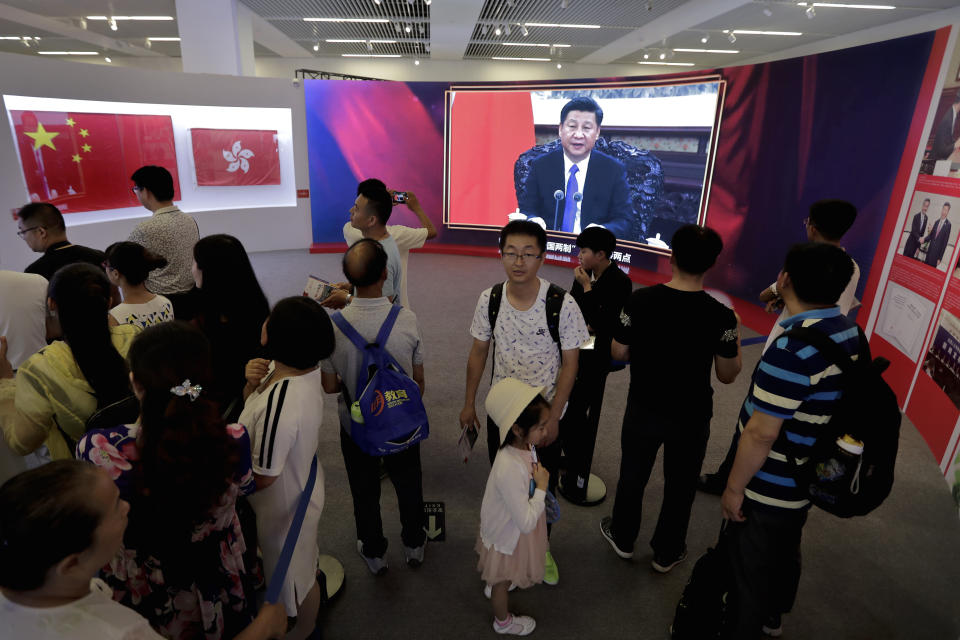 FILE - In this Sunday, July 2, 2017, file photo, visitors tour at an exhibition showcasing the 20th anniversary of the return of Hong Kong to China as a screen shows Chinese President Xi Jinping delivering a speech, at National Museum in Beijing. (AP Photo/Andy Wong, File)