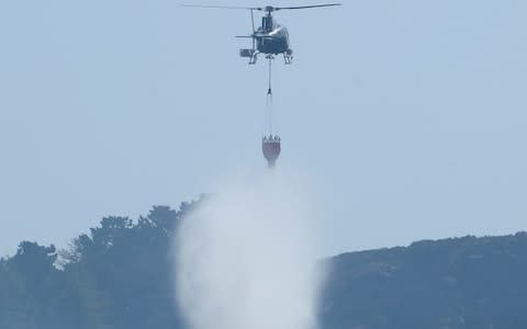 Firefighters use a helicopter to drop water as they tackle the large fire which continues to burn - Credit: Danny Lawson/PA