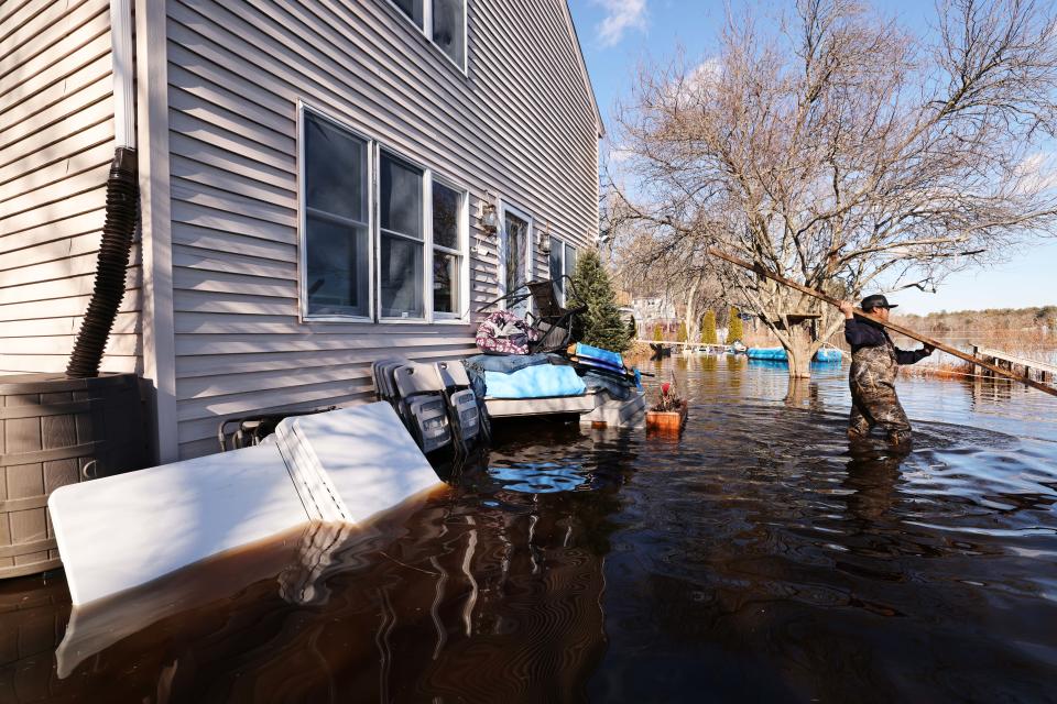 Ian Jazon wades through his flooded front yard on Bixby Drive, which borders Robbins Pond, in East Bridgewater, on Friday, Jan. 27, 2023.