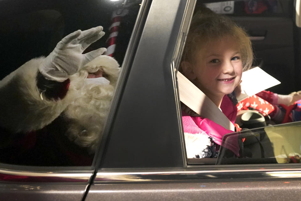 Brynn Brennan smiles at a social distant Santa as she rides past Santa's Garage on the roof of a parking garage next to Soldier Field in Chicago on Dec. 10, 2020. In this socially distant holiday season, Santa Claus is still coming to towns (and shopping malls) across America but with a few 2020 rules in effect. (AP Photo/Charles Rex Arbogast)