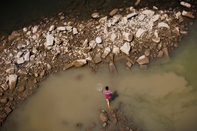 A man walks in the Yangtze river that is approaching record-low water levels during a regional drought in Chongqing