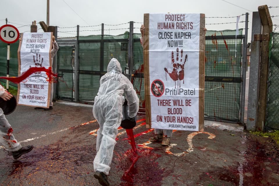 Activists take radical action throwing buckets of fake blood at Napier Barracks to highlight human rights violations on the 28th of January 2021 in Folkestone, United Kingdom. Activists dressed in white suits and masks, threw the fake blood through the gates of Napier Barracks to send a clear message to Priti Patel and the Home office to close Napier camp or there will be blood on your hands Following ongoing concerns over the poor living conditions at Napier barracks, and the failures in handling the inevitable Covid-19 outbreak onsite, pressure has been mounting on the Home Office to close the camp. (photo by Andrew Aitchison / In pictures via Getty Images)