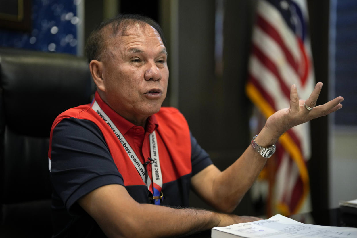 Subic Bay Metropolitan Authority Chairman and Administrator Rolen C. Paulino gestures beside a U.S. flag inside his office in what used to be America's largest overseas naval base at Olongapo city, Zambales province, northwest of Manila, Philippines on Monday Feb. 6, 2023. The U.S. has been rebuilding its military might in the Philippines after more than 30 years and reinforcing an arc of military alliances in Asia in a starkly different post-Cold War era when the perceived new regional threat is an increasingly belligerent China. (AP Photo/Aaron Favila)