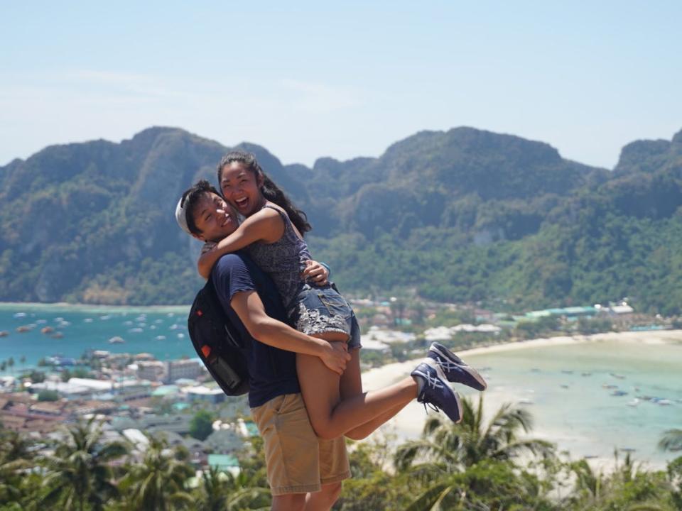 A woman being picked up by a man in front of a beach.