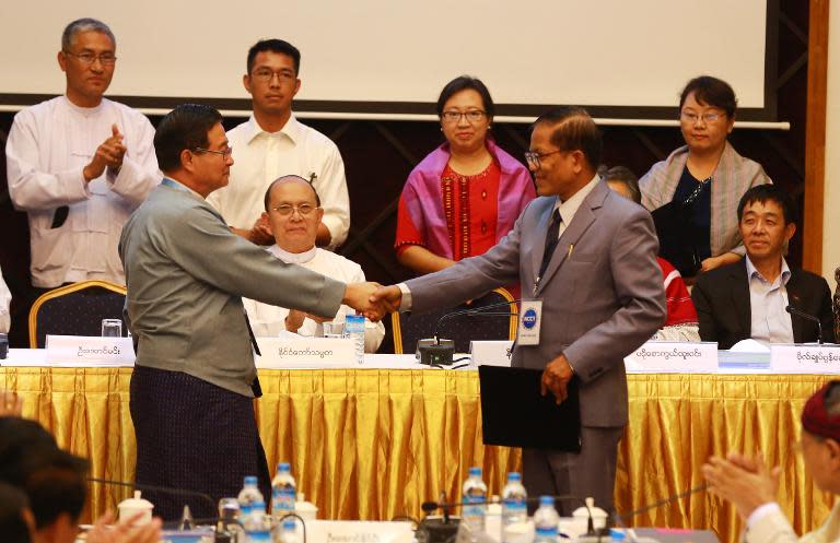 Myanmar President Thein Sein (C) looks on as Aung Min (L), of the Union Peace Working Comittee (UPWC), shakes hands with Naing Han Tha (R), of the Nationwide Ceasefire Coordinating Team (NCCT), in a ceasefire draft agreement in Yangon, March 31, 2015