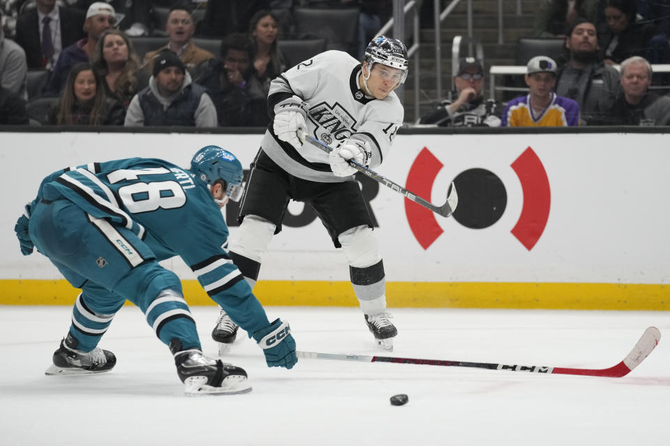 Los Angeles Kings left wing Trevor Moore (12) shoots past San Jose Sharks center Tomas Hertl (48) during the second period of an NHL hockey game Monday, Jan. 22, 2024, in Los Angeles. (AP Photo/Ashley Landis)