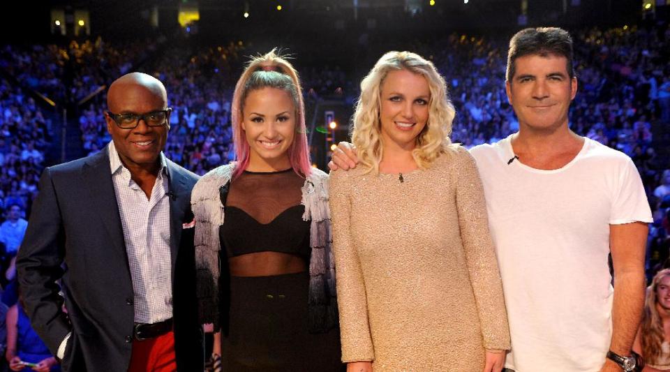 This June 2012 photo released by FOX shows judges, from left, L.A. Reid, Demi Lovato, Britney Spears and Simon Cowell on the set of "The X Factor." The contest between "The Voice" and "The X Factor" is escalating after NBC scheduled its "Voice" against Wednesday's second-season debut of Fox's "X Factor." (AP Photo/FOX, Ray Mickshaw)