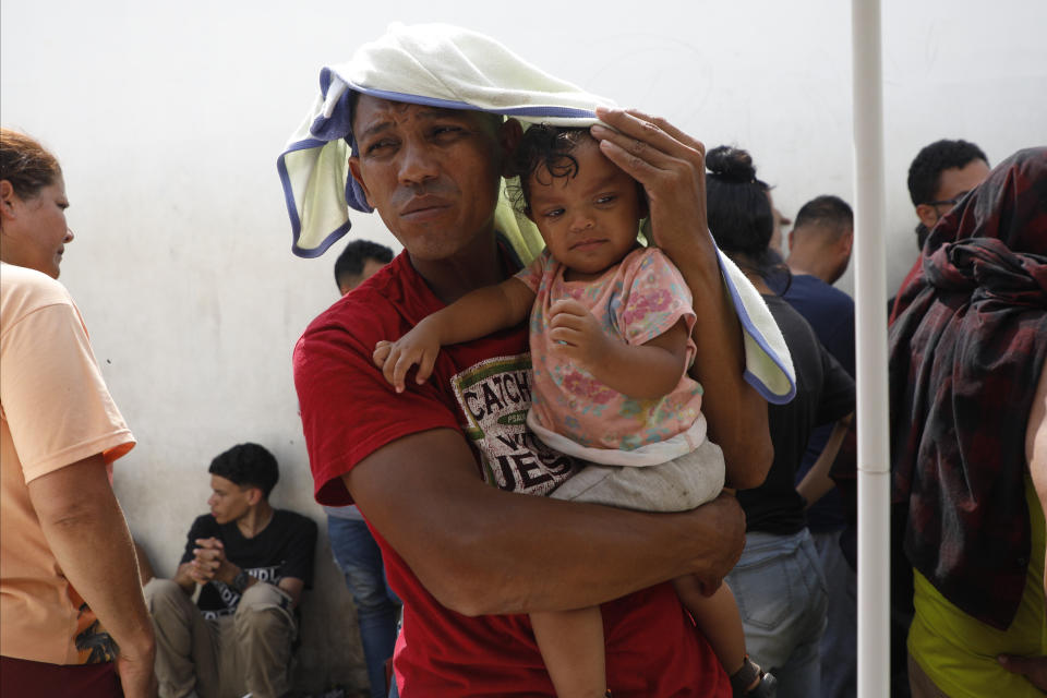 A migrant and his daughter cover themselves from the sun, as they wait for a Honduras Migration transit permit to continue their way north to Guatemala, and hopefully make it to the Mexico-United States border, in Danlí, Honduras, Wednesday, Oct. 11, 2023. According to Honduras' immigration agency, at the country's southern border with Nicaragua, more than 18,300 migrants entered the town last week. (AP Photo/Elmer Martinez)