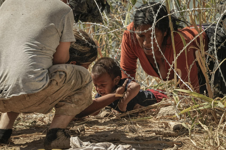 Migrants who crossed into the U.S. from Mexico pass under concertina wire along the Rio Grande river, Thursday, Sept. 21, 2023, in Eagle Pass, Texas. The image was part of a series by Associated Press photographers Ivan Valencia, Eduardo Verdugo, Felix Marquez, Marco Ugarte Fernando Llano, Eric Gay, Gregory Bull and Christian Chavez that won the 2024 Pulitzer Prize for feature photography. (AP Photo/Eric Gay)