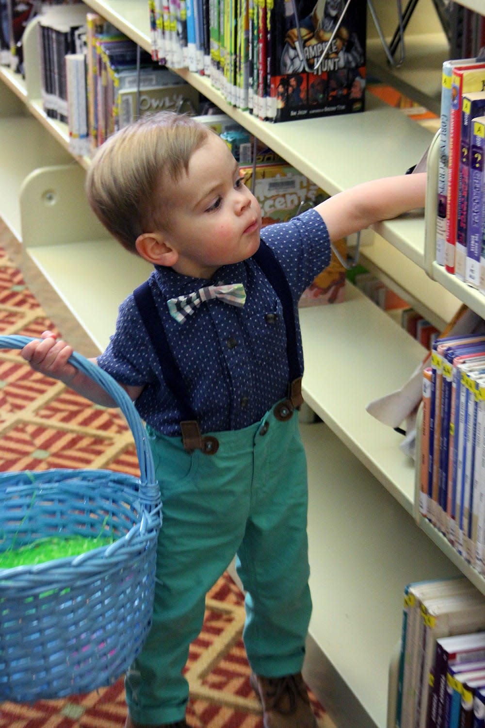 Cairo Coubey searches between the books at the Petoskey District Library for Easter eggs on March 31, 2021.