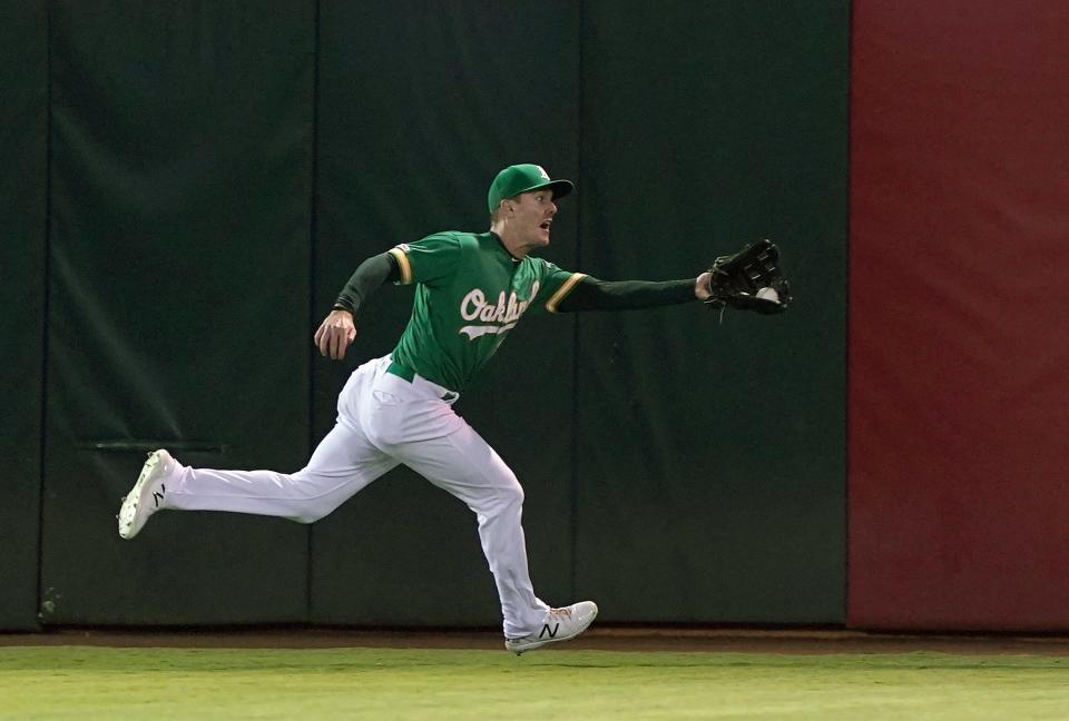 A's centerfielder Mark Canha stretches out and makes running catch on a ball hit into the right-center field gap by the Brewers Eric Thames with the bases loaded and two outs in the top of the eighth inning.