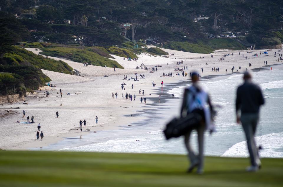 A golfer and his caddy walk down the fairway as the Carmel beach is seen in the background during the 2022 AT&T Pebble Beach Pro-Am golf tournament on Saturday, Feb. 5, 2022. 