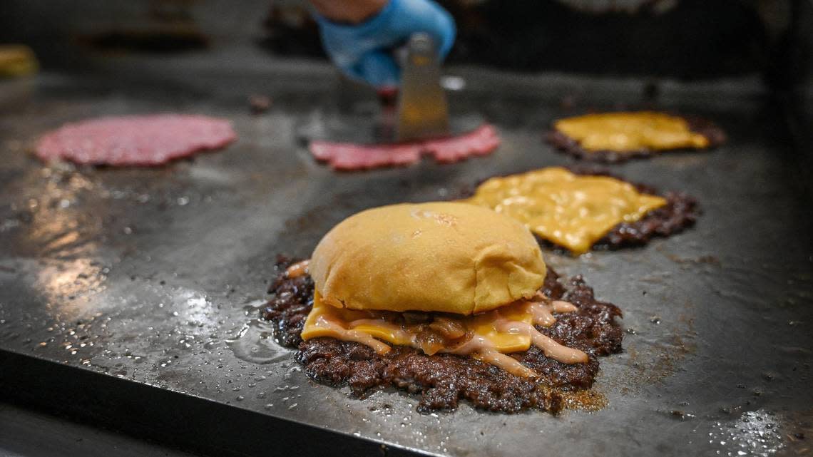 An original smash burger, prepared with grilled onions, cheese and special sauce, sizzle on the grill with others at Hammy’s Smash Burgers on West Shaw Avenue on Tuesday, Oct. 25, 2022. The new restaurant has been open about two weeks in the former Chubby’s.