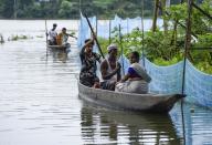 Villagers use a country boat to move across a flooded locality in Kamrup district of Assam, in India on 14 July 2020. (Photo by David Talukdar/NurPhoto via Getty Images)