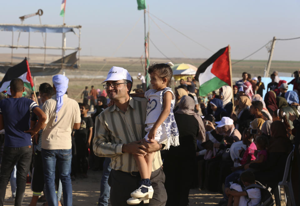 In this Sept. 25, 2019 photo, Palestinian activist Ahmed Abu Artima holds his daughter during an alternative protest he organized near the separation fence between the Gaza Strip and Israel, east of Gaza City. Gaza’s Hamas rulers are facing a rare and growing chorus of criticism, with little to show after 18 months of mass protests along the Israeli border organized by the Palestinian militant group. Gazans are increasingly questioning the high number of casualties and lack of success in lifting the Israeli blockade. Against this backdrop, Artima has launched his own peaceful version of the protest. (AP Photo/Adel Hana)
