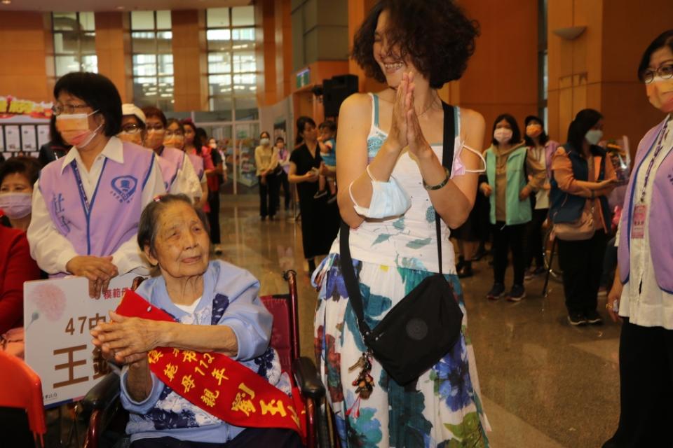 《圖說》板橋區的陳美潔帶著坐在輪椅上98歲的模範母親劉玉純，用手開心舞蹈，她每晚陪母親入眠感覺很幸福。〈社會局提供〉
