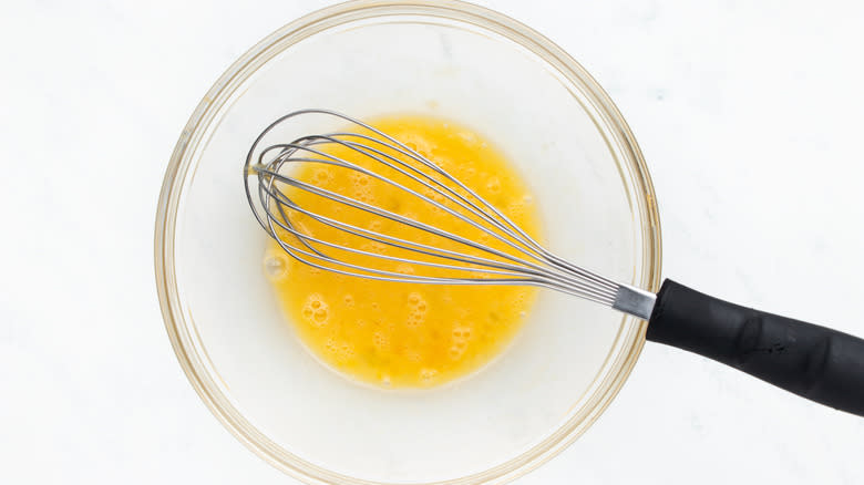 Beaten egg in bowl with whisk