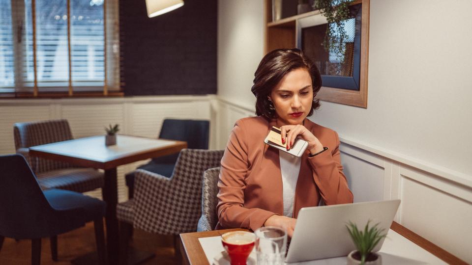 Young woman in cafe using laptop for online shopping with credit card.