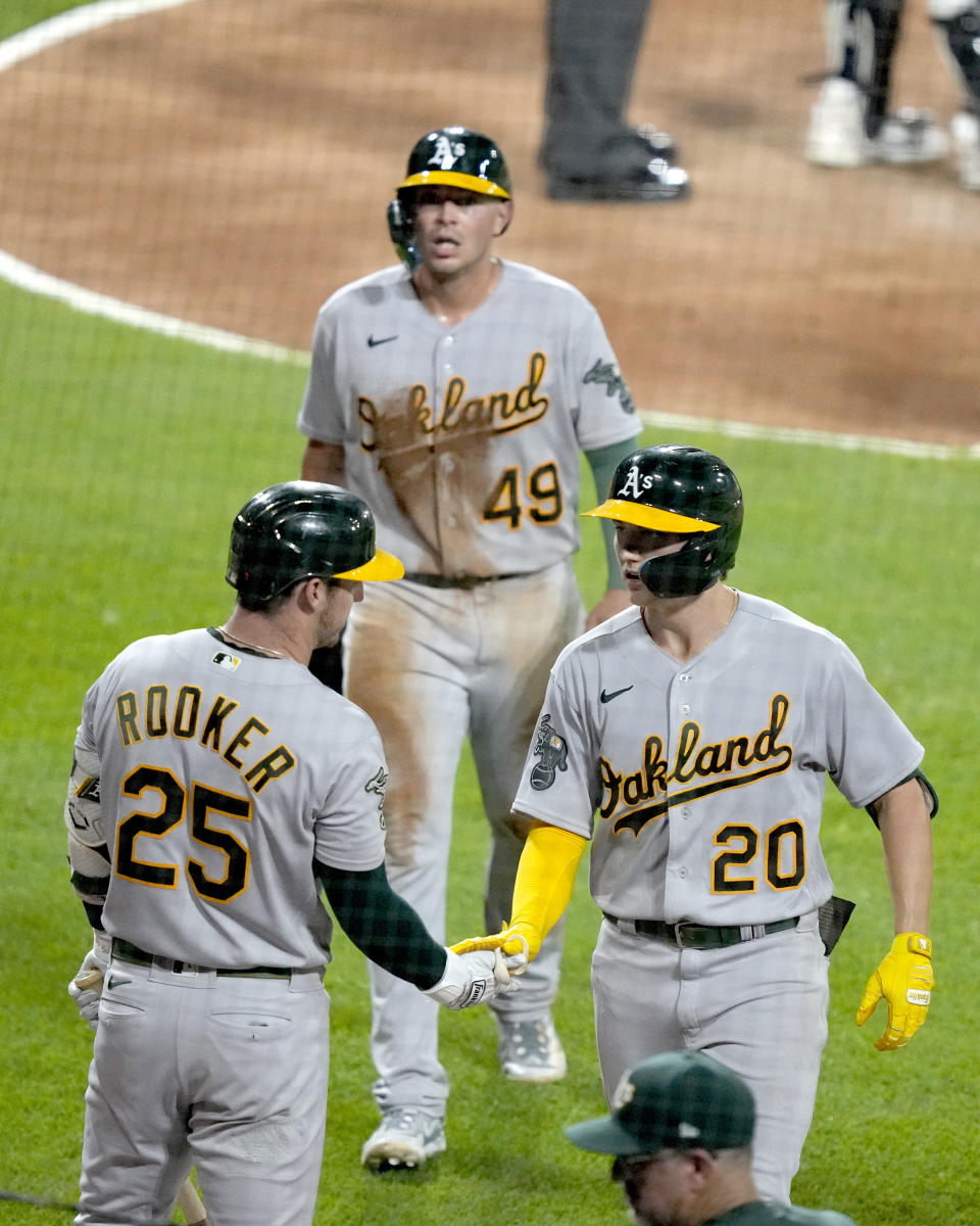 Oakland Athletics' Brent Rooker (25) greets Zack Gelof (20) outside the dugout after Geldof's two-run home run that also scored Ryan Noda (49) during the seventh inning of a baseball game against the Chicago White Sox, Thursday, Aug. 24, 2023, in Chicago. (AP Photo/Charles Rex Arbogast)