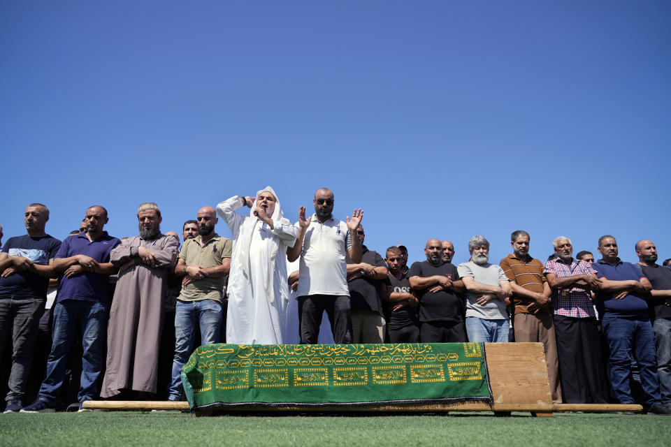 Mourners pray over the coffin of Palestinian Abdul-Al Omar Abdul-Al, 24, who was on a boat carrying migrants from Lebanon that sank in Syrian waters, during his funeral in the Palestinian refugee camp of Nahr el-Bared near the northern city of Tripoli, Lebanon, Saturday, Sept. 24, 2022. Thousands of Palestinians attended the funeral Saturday for one of the scores of migrants who lost their lives this week when their boat sank off Syria's coast. (AP Photo/Bilal Hussein)