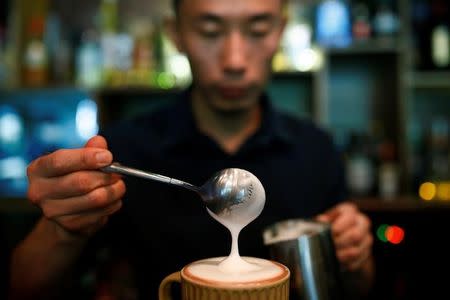 A barista pours milk into a coffee at the La Tercera cafe in Beijing, China May 6, 2017. REUTERS/Thomas Peter/Files