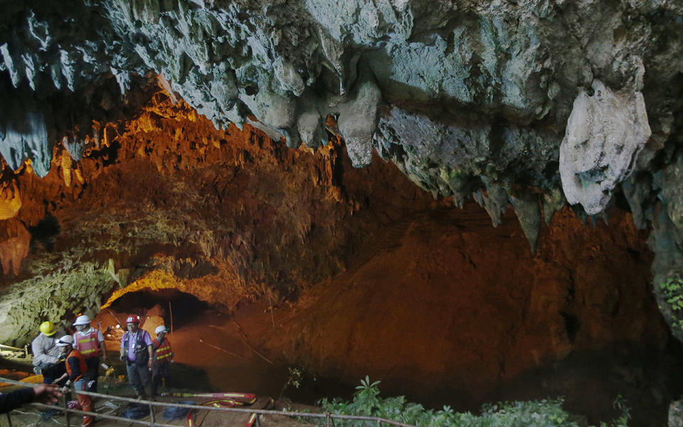 Rescue personnel walk out of the entrance to the cave complex. Source: AP