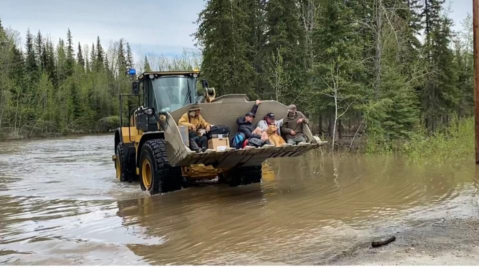 An excavator is used to carry people out of a flooded campground near Dawson City, Yukon, May 24, 2023.