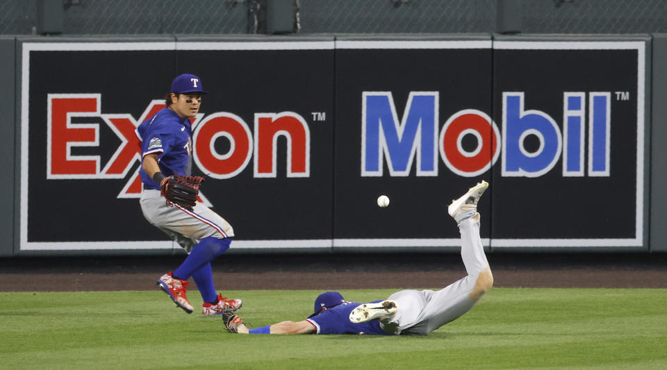 Texas Rangers center fielder Nick Solak, right, misses a ball that landed for a triple by Colorado Rockies' Charlie Blackmon, as Rangers left fielder Shin-Soo Choo comes in to retrieve the ball during the eighth inning of a baseball game Saturday, Aug. 15, 2020, in Denver. The Rangers won 6-4. (AP Photo/David Zalubowski)
