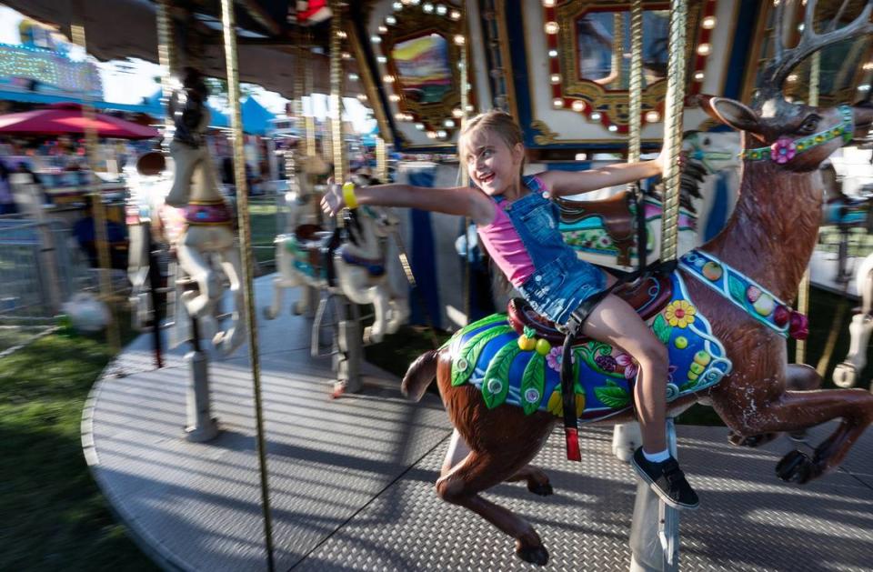 Julianna Kentra, 6, waves to her parents as she rides the carousel at the Stanislaus County Fair in Turlock, Calif., Friday, July 7, 2023.