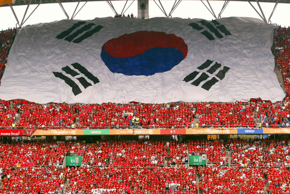 The South Korean national flag flies over a carpet of fans all dressed in red in support of their team prior to the start of their quarter-final match against Spain at the 2002 FIFA World Cup Korea/Japan in Gwangju, 22 June 2002.  The winner will meet Germany in the semifinal match on June 25 in Seoul.     AFP PHOTO/Pornchai KITTIWONGSAKUL (Photo credit should read PORNCHAI KITTIWONGSAKUL/AFP via Getty Images)