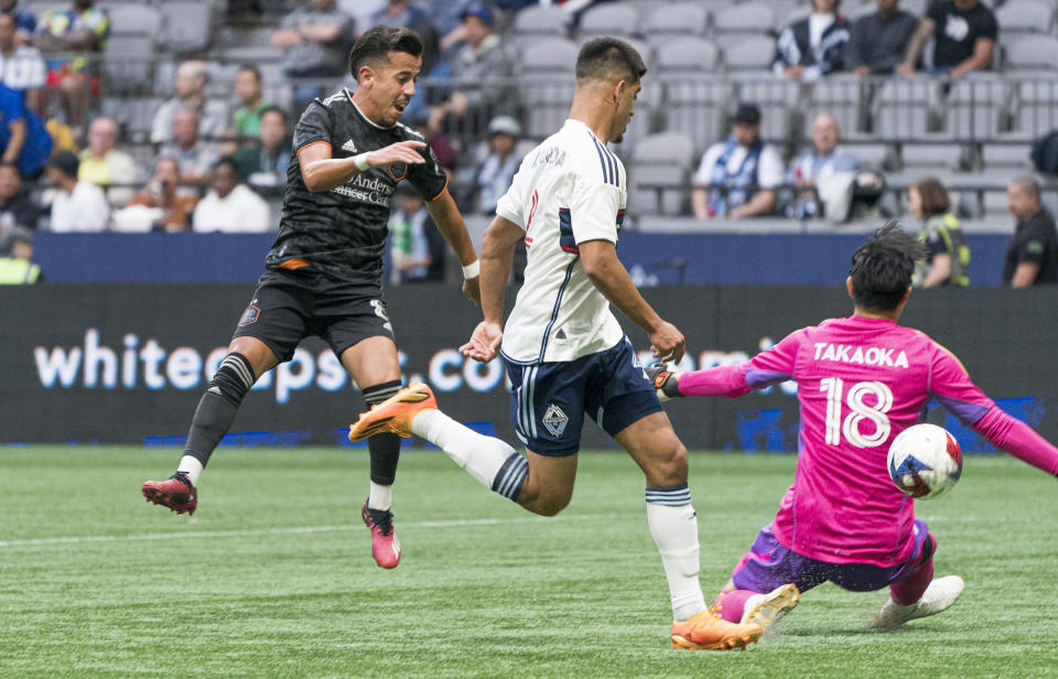 Houston Dynamo's Amine Bassi, left, kicks the ball past Vancouver Whitecaps' Mathias Laborda, center, and goalkeeper Yohei Takaoka for a goal during the first half of an MLS soccer match Wednesday, May 31, 2023, in Vancouver, British Columbia. (Rich Lam/The Canadian Press via AP)