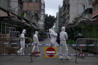 Government workers wearing personal protective equipment walk at the closed area in Jordan district, in Hong Kong, Sunday, Jan. 24, 2021. Thousands of Hong Kong residents were locked down Saturday in an unprecedented move to contain a worsening outbreak in the city, authorities said. (AP Photo/Vincent Yu)