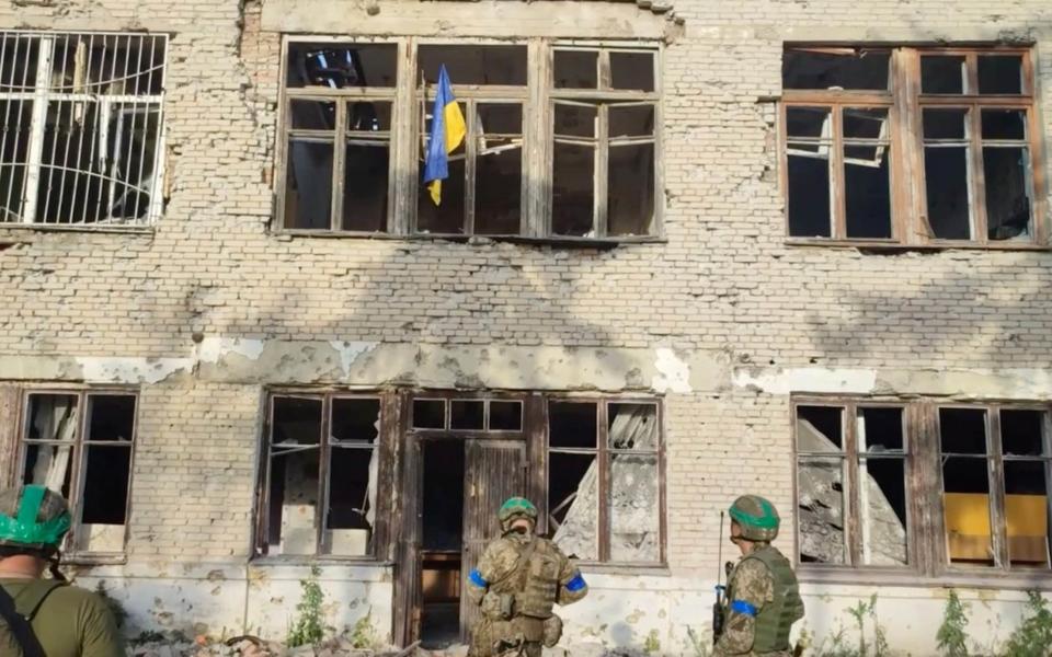 Ukrainian soldiers stand in front of a building with a Ukrainian flag on it, during an operation that claims to liberate the first village amid a counter-offensive, in a location given as Blahodatne, Donetsk Region, Ukraine, in this screengrab taken from a handout video released on June 11, 2023. 68th Separate Hunting Brigade 'Oleksy Dovbusha'/Handout via REUTERS THIS IMAGE HAS BEEN SUPPLIED BY A THIRD PARTY. NO RESALES. NO ARCHIVES. MANDATORY CREDIT. REUTERS WAS NOT ABLE TO INDEPENDENTLY VERIFY THE LOCATION OF THE VIDEO AND THE DATE IT WAS FILMED. - 68th Separate Hunting Brigade 'Oleksy Dovbusha'/Handout via REUTERS 