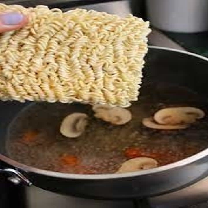 Ramen noodles going into a pot of soup.