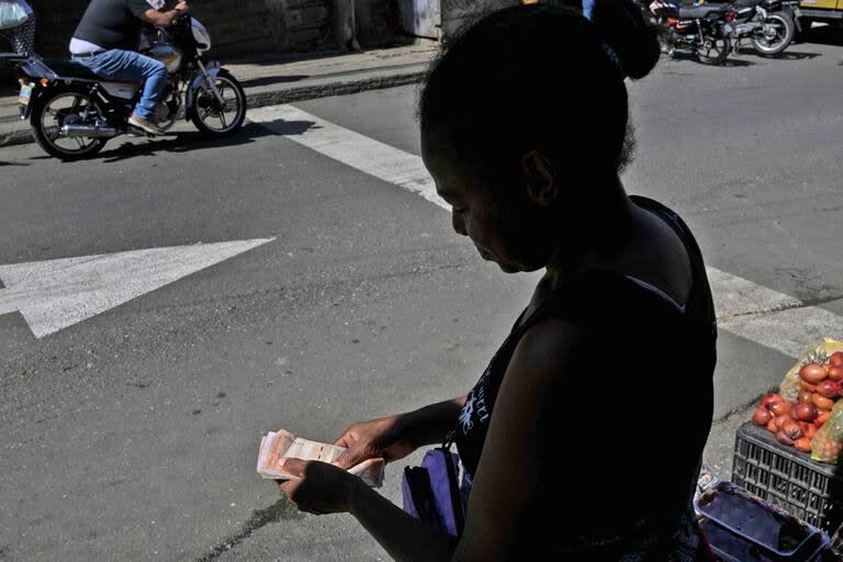 Una mujer cuenta billetes de bolívares en el barrio de Petare, en Caracas, el 24 de julio de 2024, antes de las elecciones 