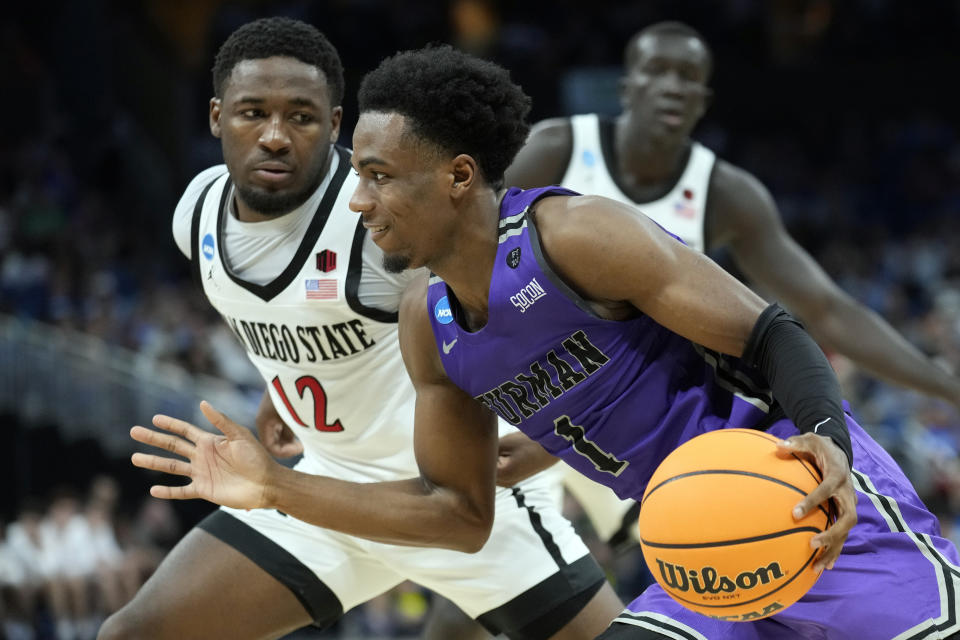 Furman guard JP Pegues (1) drives around San Diego State guard Darrion Trammell (12) during the second half of a second-round college basketball game in the NCAA Tournament Saturday, March 18, 2023, in Orlando, Fla. (AP Photo/Chris O'Meara)