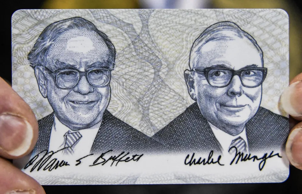 A woman shows a card with photos of Warren Buffett (L) and Charlie Munger (R) during the Shareholder Shopping Day at the Berkshire Hathaway Shareholders Meeting at CHI Health Center in Omaha, Nebraska on April 29, 2022. (Photo by CHANDAN KHANNA / AFP)