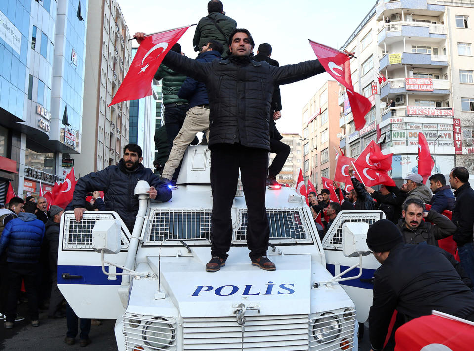 A demonstrator waves Turkish flags on top of a police vehicle in Diyarbakir