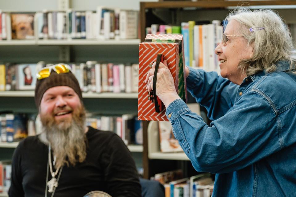Pauline Lanzer from New Philadelphia plays a children's toy accordion while antiques appraiser Jason Adams watches at the New Philadelphia branch of the Tuscarawas County Library.