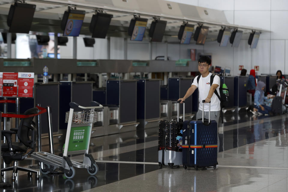 A traveller pushes his luggage past closed check-in counters at the airport in Hong Kong, Wednesday, Aug. 14, 2019. Flight operations resumed at the airport Wednesday morning after two days of disruptions marked by outbursts of violence highlighting the hardening positions of pro-democracy protesters and the authorities in the Chinese city that's a major international travel hub. (AP Photo/Vincent Thian)