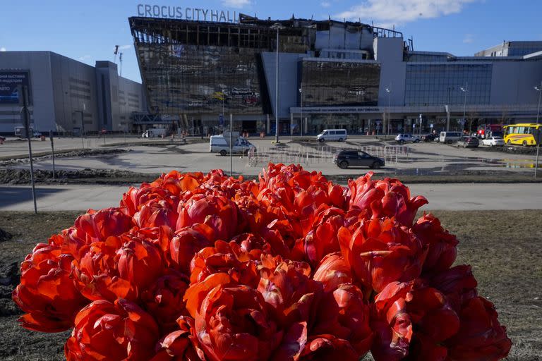 Un ramo de flores colocado en la cerca frente a la sala de conciertos incendiada Crocus City Hall en las afueras de Moscú, 27 de marzo de 2024. El principal organismo investigador de Rusia dijo el jueves 28 de marzo de 2024 que se ha detenido a un nuevo sospechoso por complicidad en el ataque a una sala de conciertos en las afueras de Moscú que dejó 143 muertos. (AP Foto/Alexander Zemlianichenko)