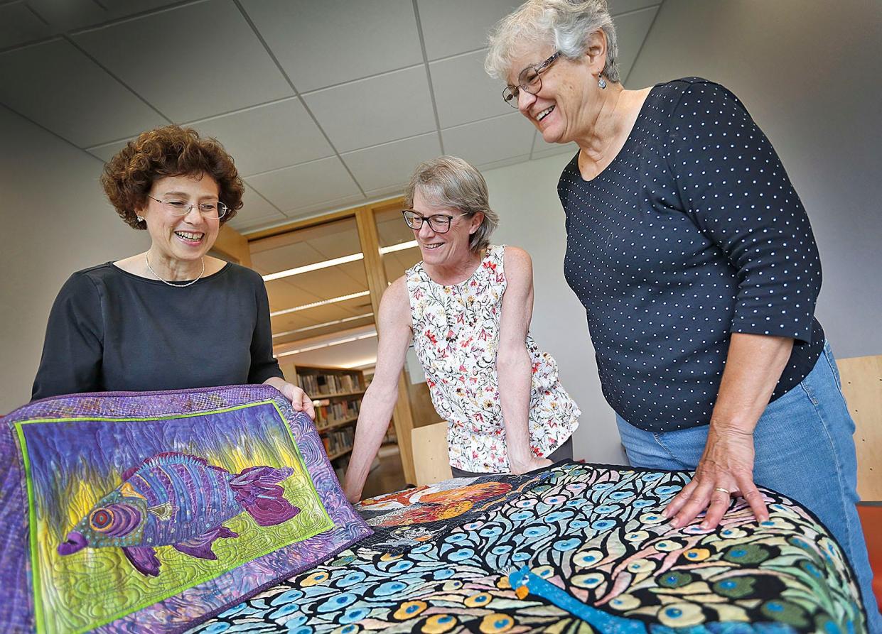 From left, Rosemarie Gentile, Holly Carpenter and featured quilter Nancy Robertson, of the Herring Run Quilters' Guild, look over quilts made by members. The guild is preparing for a large show in Marshfield the weekend of Sept. 24, 2022.