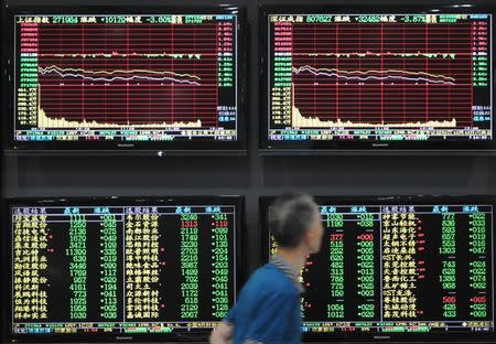 A man walks past screens showing stock information at a brokerage house in Jiujiang, Jiangxi province, China October 8, 2018. REUTERS/Stringer/Files