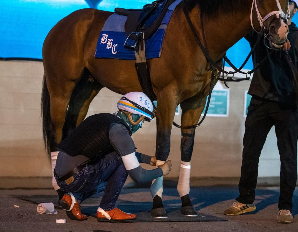 Exercise rider Joseph Santiago, seen wrapping a horse's leg at Churchill Downs, wore a white arm band in honor of the late Callie Witt, a rider who died recently at Keeneland. May 5, 2022