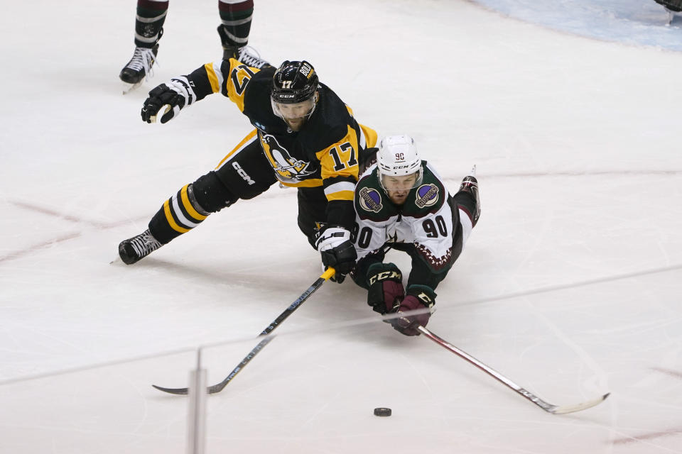 Pittsburgh Penguins' Bryan Rust (17) and Arizona Coyotes' J.J. Moser reach for control of the puck during the first period of an NHL hockey game Thursday, Oct. 13, 2022, in Pittsburgh. (AP Photo/Keith Srakocic)