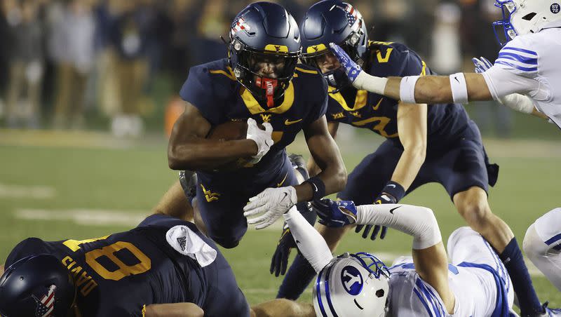 West Virginia’s Traylon Ray, top, runs over BYU players during the Mountaineers’ victory on Saturday, Nov. 4, 2023, in Morgantown.