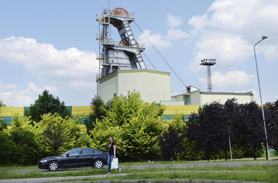 A woman passes the Wujek coal mine in the Polish region of Silesia during a pause in operations in Katowice, Poland, Saturday, July 4, 2020. The coronavirus has ripped through Poland's coal mines, paralyzing an already-troubled industry, forcing many to stay home from work and triggering a three-week closure of many state-run mines. (AP Photo/Czarek Sokolowski)