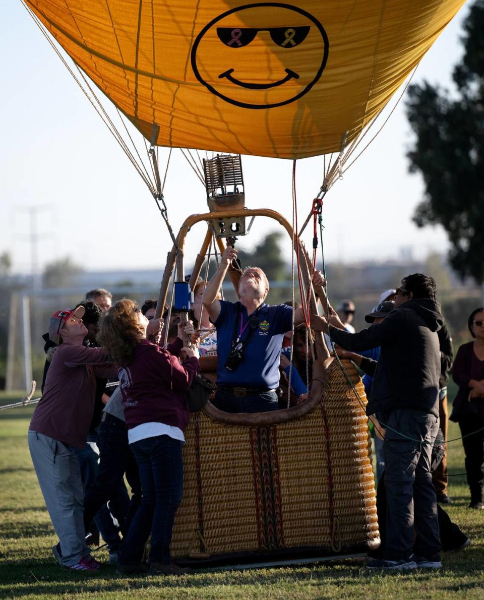 Volunteers hold down the basket as pilot Dana Thornton uses a burner to heat air for his balloon FreeSpirit during the Skies the Limit Ceres Balloon Festival at River Bluff Regional Park In Ceres, Calif., Saturday, June 15, 2024.