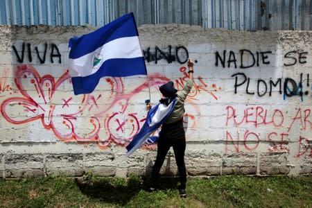 An anti-government protester sprays graffiti paint on a wall during a protest against Nicaraguan President Daniel Ortega's government in Managua